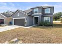 Two-story house with gray exterior, brown garage door, and landscaping at 14143 Wake Robin Dr, Brooksville, FL 34604