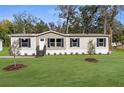 Tan manufactured home with black shutters and well-maintained lawn at 18077 Evening Star Ave, Brooksville, FL 34604