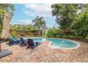 Inviting kidney-shaped pool with brick patio and lounge chairs at 2413 Hazelwood Ln, Clearwater, FL 33763