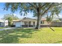 House exterior featuring a large tree, manicured lawn, and American flag at 6920 Medlar Dr, New Port Richey, FL 34653