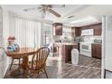Galley-style kitchen with dark wood cabinets, white appliances, and a small dining area at 10841 Gawain Rd, Port Richey, FL 34668