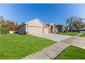 Tan house with brown roof, two-car garage, and lush green lawn at 13793 Dunwoody Dr, Spring Hill, FL 34609