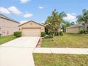 Tan house with a two-car garage and landscaped lawn at 18732 Dobson Dr, Hudson, FL 34667