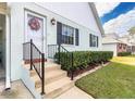 Front entrance with steps, black railing, and lush green shrubs at 6650 Hickorywood Ln # 6650, New Port Richey, FL 34653