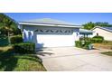 Two-car garage with white doors and landscaping at 13313 Brigham Ln, Hudson, FL 34667