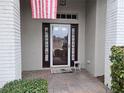 Front entry with glass door, brick columns, and welcome mat at 18049 Tarrington Pl, Hudson, FL 34667