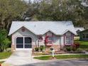 Cute single-story house with a gray roof, red accents, and a screened garage at 4912 Enfield Ct, New Port Richey, FL 34655