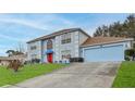 Two-story house with light blue exterior, red door and attached garage at 5182 Colchester Ave, Spring Hill, FL 34608