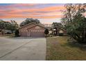 House exterior at sunset, three-car garage at 18164 Winding Oaks Blvd, Hudson, FL 34667