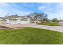 A single-Gathering home has a three-car garage and large front yard on a sunny day at 5286 Hamlet Cir, Spring Hill, FL 34606