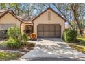 Front view of a tan house with a brown garage door and landscaping at 6663 Water Oak Ct, Spring Hill, FL 34606