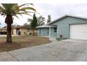 Newly renovated light blue house with a white garage door and landscaped yard at 8703 Robilina Rd, Port Richey, FL 34668