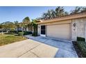 Tan brick house exterior with a two-car garage and landscaping at 9338 Clearmeadow Ln, New Port Richey, FL 34655