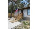 Steps leading to the front entrance of a manufactured home, featuring a wooden railing and a US flag at 11743 Purdue St, New Port Richey, FL 34654