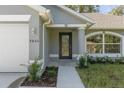 Front entryway with a modern black door, and a landscaped walkway leading to the home at 12040 Pine Warbler Ave, Brooksville, FL 34614