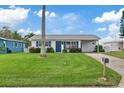 Cute bungalow style home with a grassy yard, palm tree, and blue door at 4424 Floramar Ter, New Port Richey, FL 34652