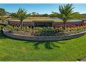 Attractive community entrance sign surrounded by vibrant flowers, lush landscaping and palm trees at 1082 Dartford Dr, Tarpon Springs, FL 34688