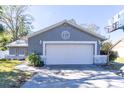 Gray house with white garage door, stone accents, and a basketball hoop in the yard at 14004 Cascade Ln, Tampa, FL 33618