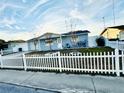 Cozy home with a white picket fence, a well-kept lawn and beautiful blue skies at 1415 Weyford Ln, Holiday, FL 34691