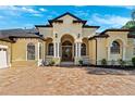 Elegant home exterior featuring a brick paver driveway and arched entryway at 20200 Lace Cascade Rd, Land O Lakes, FL 34637