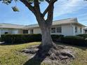 Home exterior with mature tree providing shade, complimented by a well-kept lawn and landscaping at 2718 Highlands Blvd # A, Palm Harbor, FL 34684