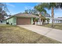 Green house with brown garage door and a long driveway at 3497 Chadwick Ave, Spring Hill, FL 34609