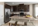 Modern kitchen with dark cabinets, granite counters, and stainless steel appliances at 6027 Wild Petunia Dr, Wimauma, FL 33598
