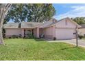 Pink one-story house with a two-car garage and well-maintained lawn at 2263 Whisper Walk Dr, Spring Hill, FL 34606