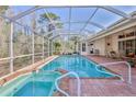 Inviting screened-in pool area featuring a spa and brick-paved patio for outdoor relaxation at 9091 Alexandria Dr, Weeki Wachee, FL 34613