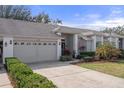 Landscaped front yard leads to this house with neutral-colored brick accents, a two-car garage, and covered entry at 11008 Torrey Pines Ct, Hudson, FL 34667