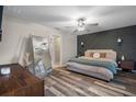 Serene main bedroom with dark accent wall, wood-look floors, ceiling fan, and ensuite bathroom at 13357 Marble Sands Ct, Hudson, FL 34669