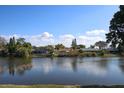 Scenic view of a serene lake surrounded by lush greenery and charming waterfront homes under a blue sky at 3526 Overland Dr, Holiday, FL 34691