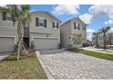 Attractive townhome showcases two-car garage, manicured landscape, paver driveway and gray stucco exterior at 4066 Cloud Hopper Way, Lutz, FL 33559
