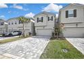 Modern townhomes featuring a two-car garage, gray stucco exterior, paver driveways and manicured landscaping at 4066 Cloud Hopper Way, Lutz, FL 33559