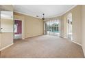 Spacious living room with neutral walls, carpet, and a large sliding glass door leading to a pool at 6112 Kinlock Ave, Spring Hill, FL 34608