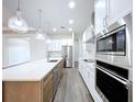 Modern kitchen with stainless steel appliances, white cabinetry, and hardwood flooring at 9065 Mississippi Run, Weeki Wachee, FL 34613
