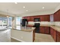 Well-equipped kitchen featuring dark wood cabinetry and a center island with a sink at 14930 Potterton Cir, Hudson, FL 34667