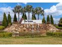 Del Webb Bexley community entrance featuring a water feature, lush landscaping, palm trees and blue skies at 18629 Coastal Shore Ter, Land O Lakes, FL 34638