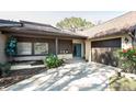 Single-story home featuring light brick, brown siding, concrete driveway, and well-maintained landscaping at 2101 Sunset Point Rd # 2706, Clearwater, FL 33765