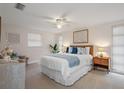 Well-lit main bedroom with a white bed with blue accents, carpet flooring, and a ceiling fan, creating a relaxing atmosphere at 5155 Norfolk Ct, New Port Richey, FL 34653