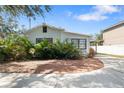 Quaint single-story house featuring a tidy front yard with mulch and lush greenery at 6305 S Macdill Ave, Tampa, FL 33611