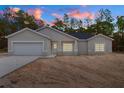 Charming single-story home featuring a two-car garage, and an inviting front entrance at dusk at 18020 Macek Rd, Weeki Wachee, FL 34614
