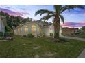 Beautiful home with a lush lawn, complemented by a striking palm tree silhouetted against a colorful evening sky at 456 Greenwich Cir, Spring Hill, FL 34609