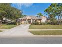 Charming one-story home with a well-manicured lawn, mature landscaping, and a long concrete driveway at 5351 Championship Cup Ln, Spring Hill, FL 34609