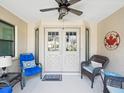 Comfortable front porch featuring double doors, ceiling fan and welcoming decor at 6785 Poinciana Ct, Spring Hill, FL 34606