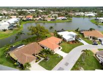 Aerial view of single-story home with tile roof, situated on a corner lot near a lake at 1654 Waxwing Ct, Venice, FL 34293