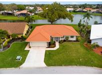 Single-story home with orange tile roof, large yard, and water view at 1654 Waxwing Ct, Venice, FL 34293