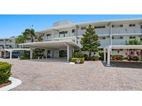 Building exterior featuring covered parking and landscaped grounds at 100 Sands Point Rd # 305, Longboat Key, FL 34228