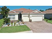 Charming single-story home featuring a well-manicured lawn, paver driveway, and a beautiful tile roof at 1934 Mesic Hammock Way, Venice, FL 34292