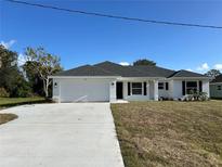Newly constructed home with a white exterior, gray roof, and a two-car garage at 2738 N Chamberlain Blvd, North Port, FL 34286